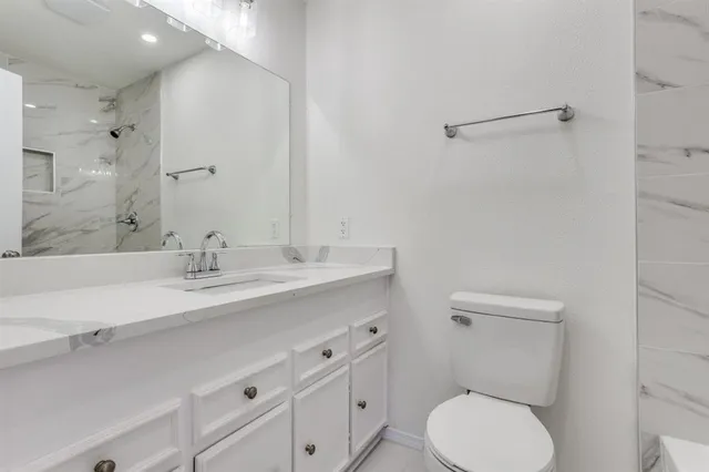 a bathroom with a toilet sink a mirror and vanity