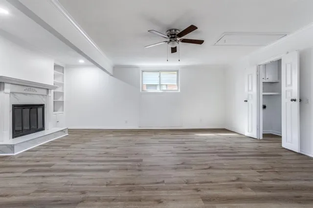 a view of an empty room with wooden floor fireplace and a window