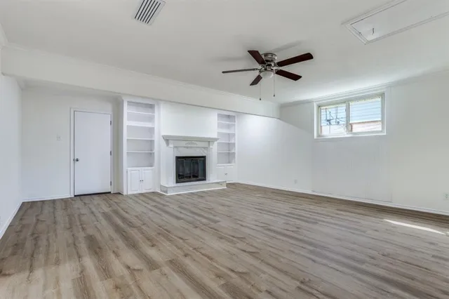 a view of empty room with wooden floor and fireplace