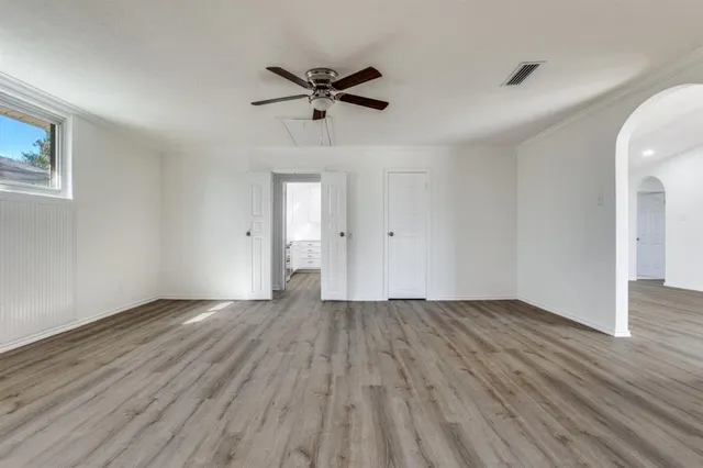an empty room with wooden floor closet and windows