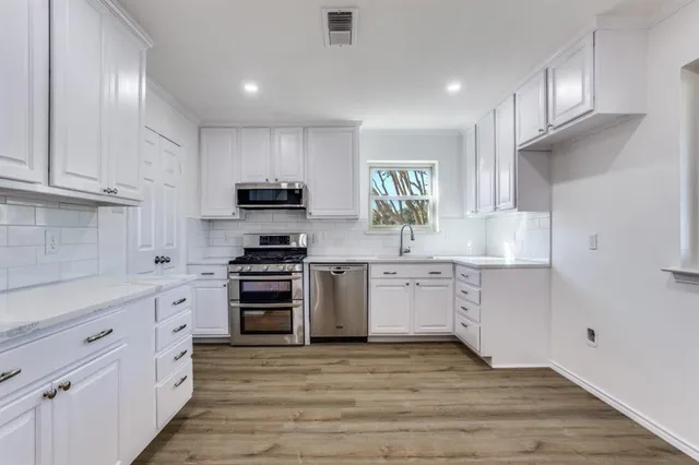 a kitchen with granite countertop white cabinets and stainless steel appliances