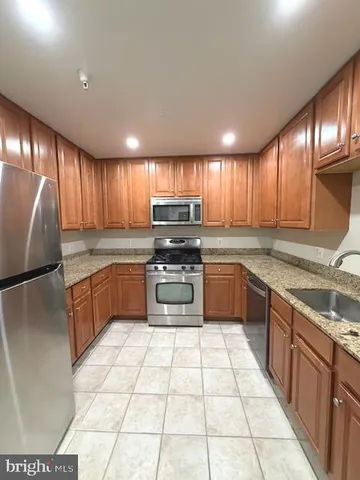 a kitchen with a stove a sink dishwasher a refrigerator and cabinets with wooden floor