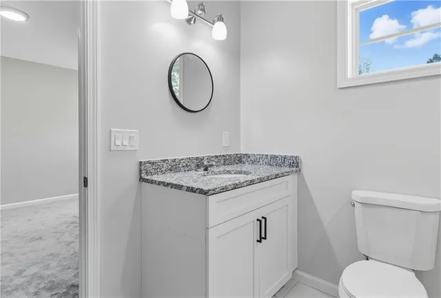 a bathroom with a granite countertop toilet and a sink