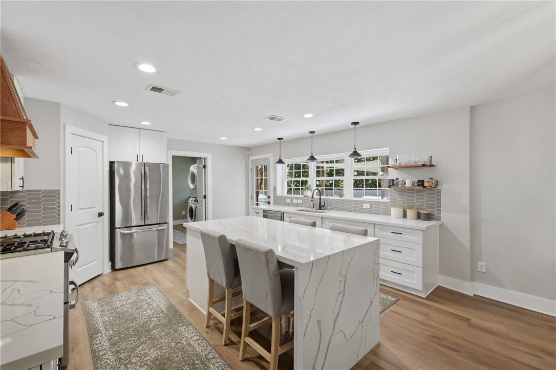 515 Crescent Drive Bryan, TX 77801 - Photo 12 of 43 Contemporary kitchen featuring a waterfall island, stainless steel gas appliances, recessed lighting, wood-finish flooring, and a tile backsplash