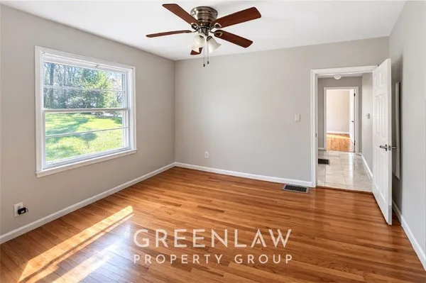 a view of empty room with wooden floor and fan