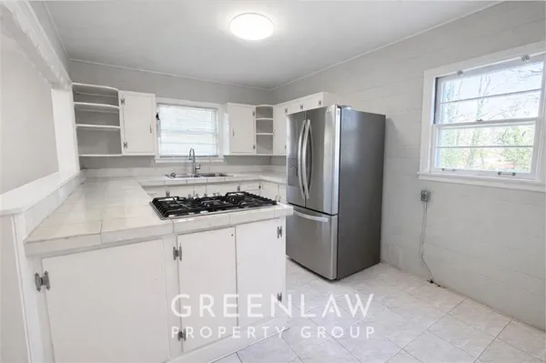 a kitchen with stainless steel appliances a refrigerator a stove a sink and a window