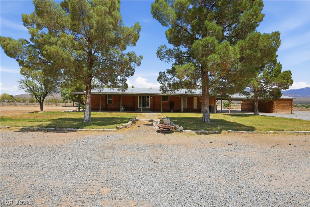 1531 West Harris Farm Road Pahrump, NV 89060 - Photo 7 of 37 A charming log home awaits, nestled amidst verdant landscaping and mature shade trees.