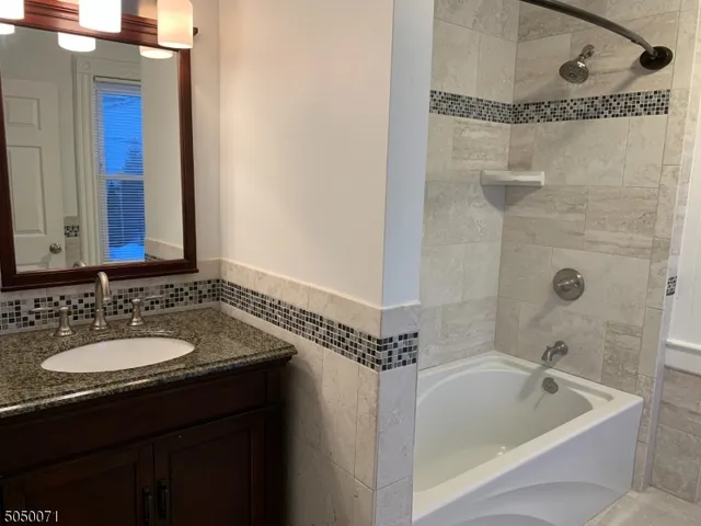 a bathroom with a granite countertop sink a shower and a mirror