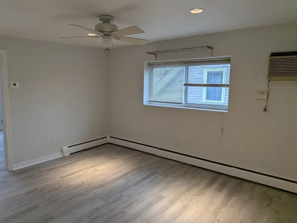 an empty room with wooden floor chandelier fan and windows