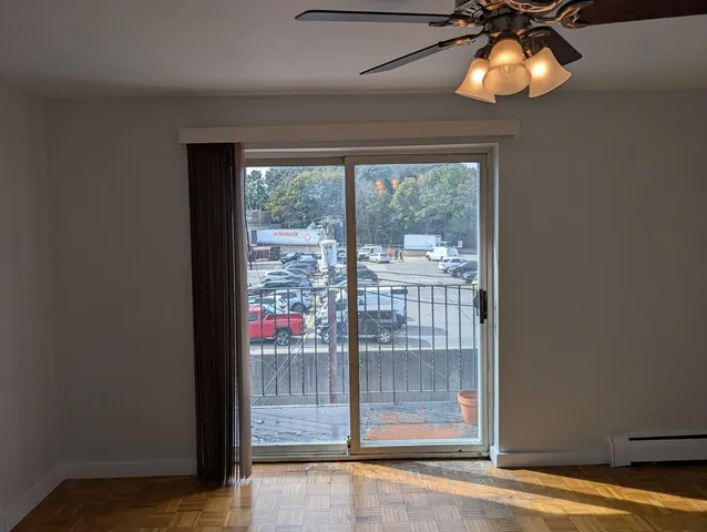 a view of empty room with wooden floor and fan
