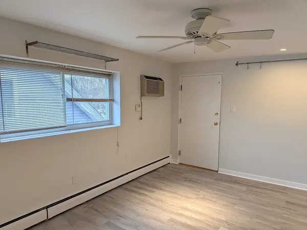 a view of empty room with wooden floor and fan