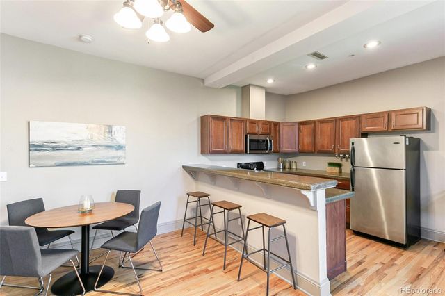 a kitchen with stainless steel appliances a dining table chairs and refrigerator