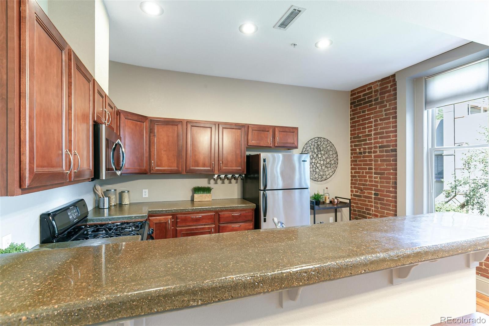 3211 Zuni Street, Unit 4 Denver, CO 80211 - Photo 12 of 35 a kitchen with stainless steel appliances granite countertop a refrigerator a sink a stove a washer dryer and a dining table with wooden cabinet