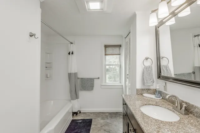 a bathroom with a granite countertop sink a mirror and a bathtub