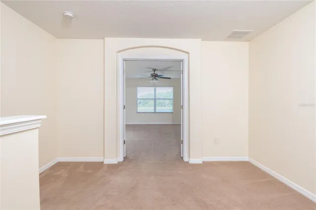 an empty room with ceiling fan and windows