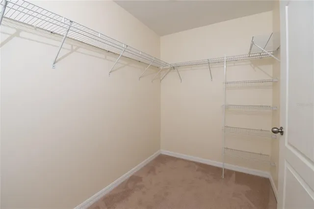 an empty room with chandelier fan and windows