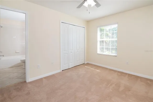 an empty room with a chandelier fan and windows