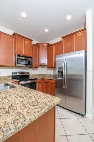 a kitchen with stainless steel appliances granite countertop a refrigerator a stove top oven and a sink with granite countertops