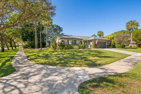 a view of a house with a big yard potted plants and large tree