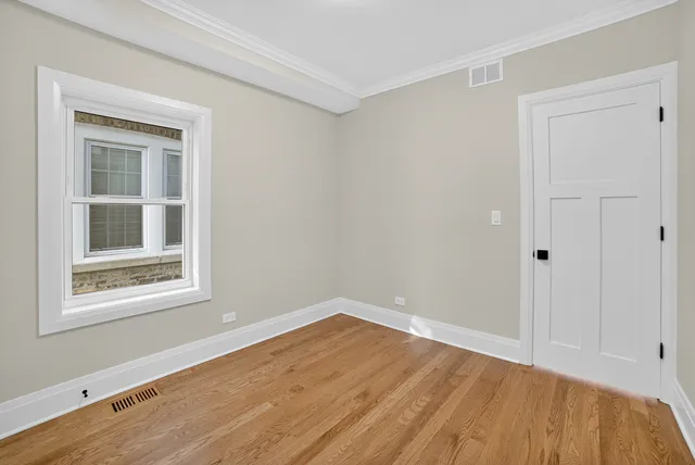 a view of empty room with wooden floor and fan