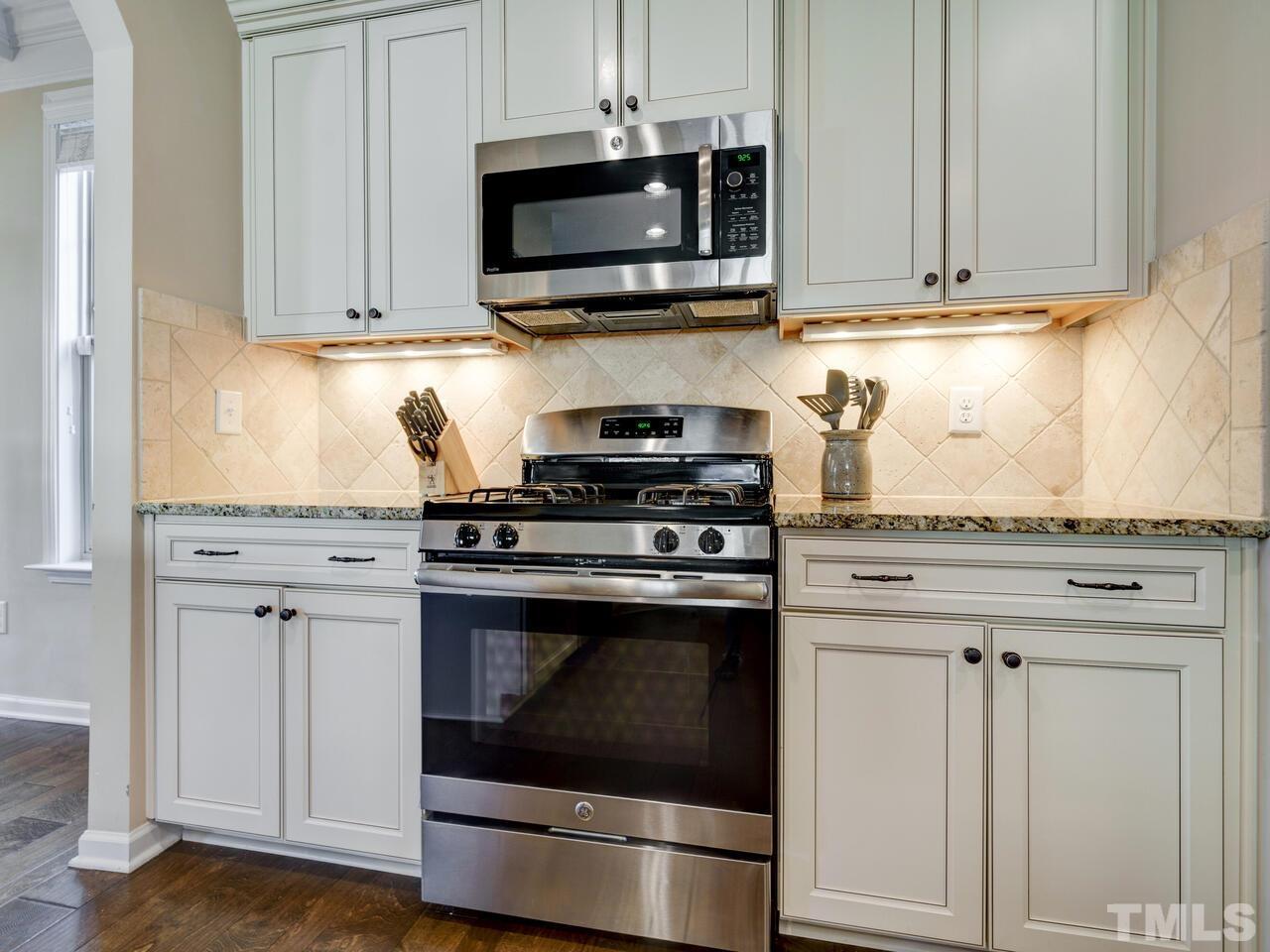 207 Maple Walk Street Durham, NC 27703 - Photo 23 of 50 a kitchen with granite countertop white cabinets stainless steel appliances and wooden cabinets