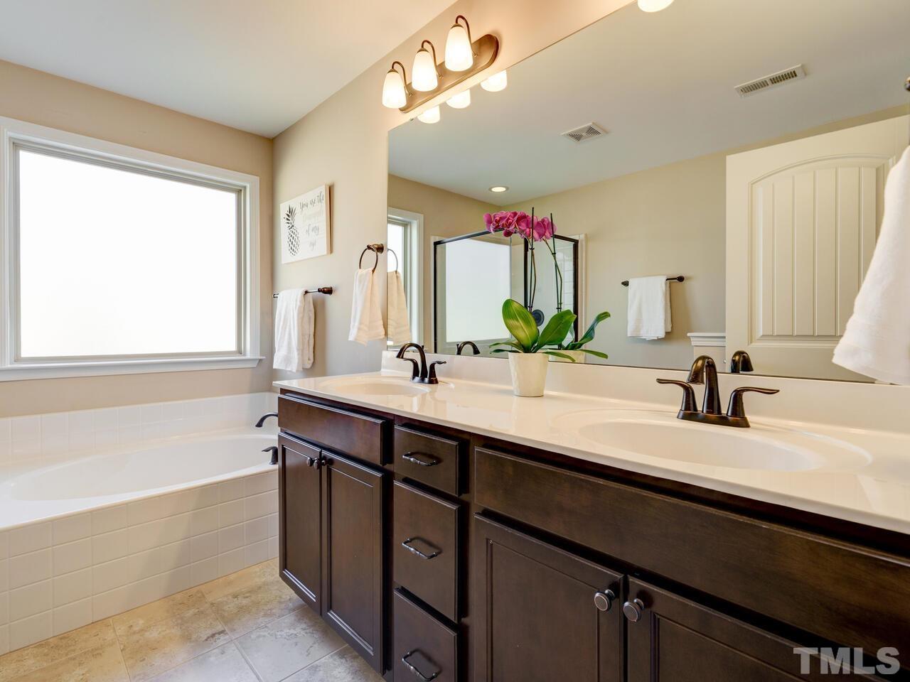 207 Maple Walk Street Durham, NC 27703 - Photo 35 of 50 a bathroom with a double vanity sink a mirror and a bathtub
