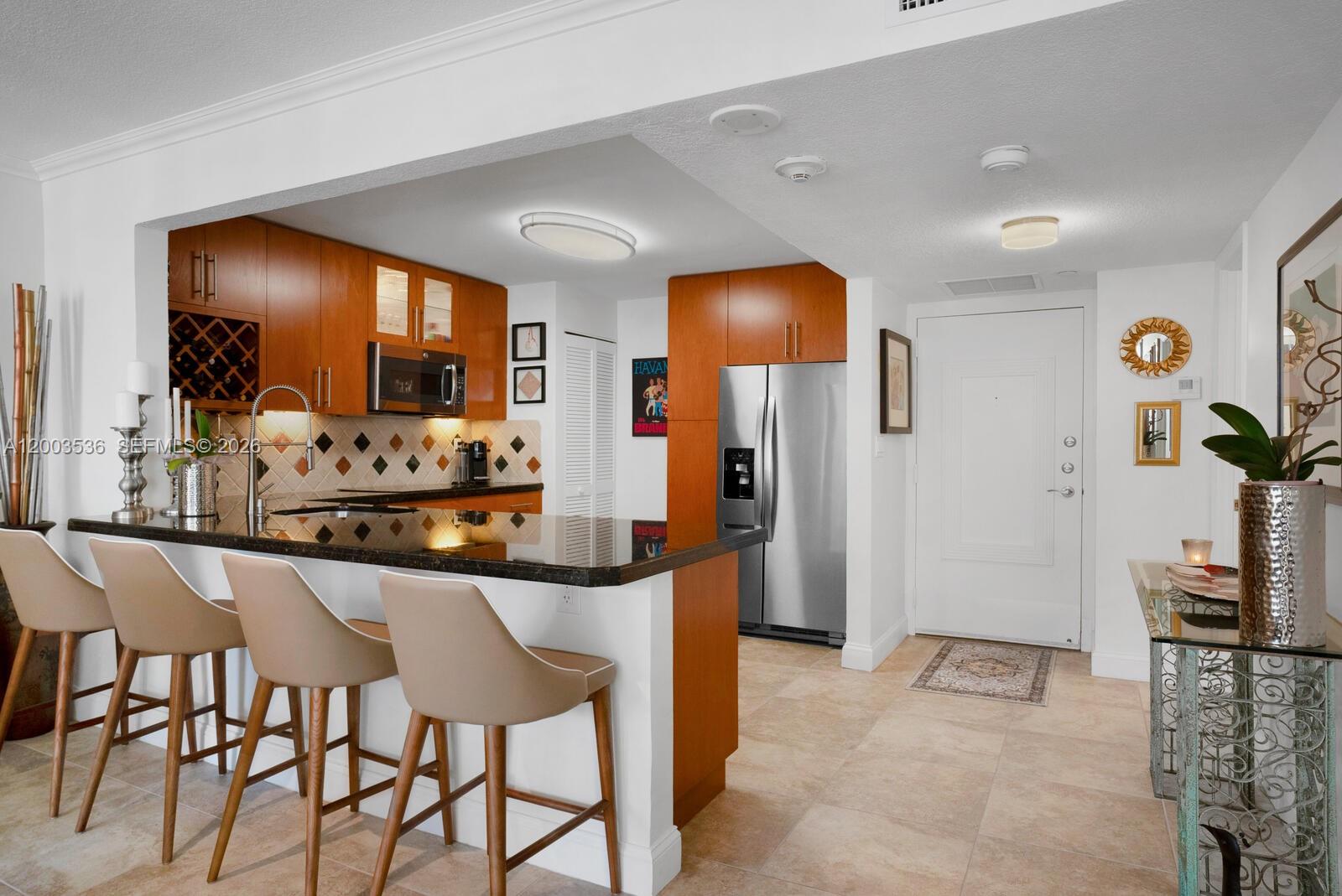 1925 Brickell Avenue, Unit 1003 Miami, FL 33129 - Photo 7 of 16 a kitchen with stainless steel appliances kitchen island granite countertop dining table chairs and a refrigerator