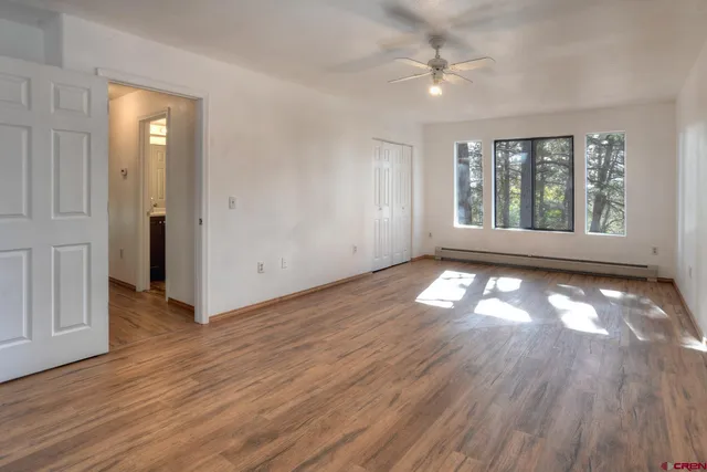 a view of empty room with wooden floor and fan