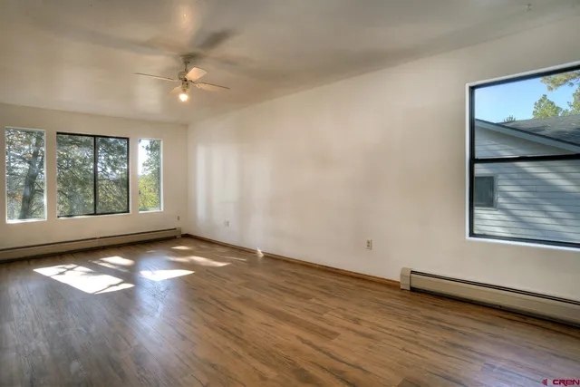 an empty room with wooden floor and windows