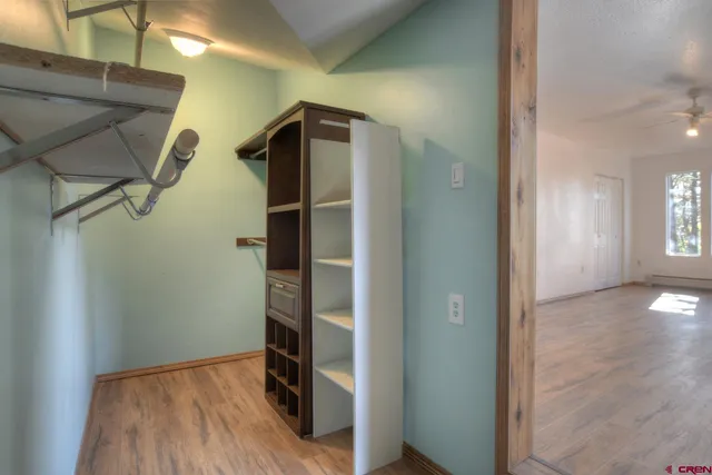 a view of empty room with wooden floor and fan