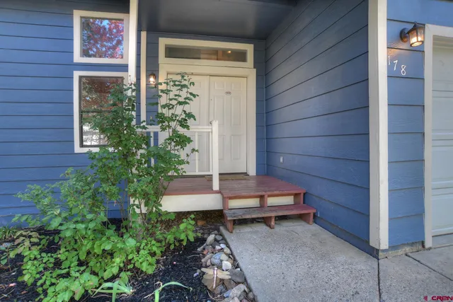 a backyard of a house with wooden chairs and potted plants