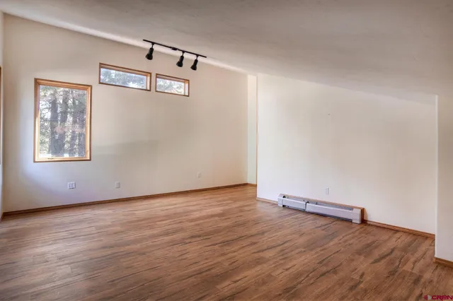 an empty room with wooden floor and windows