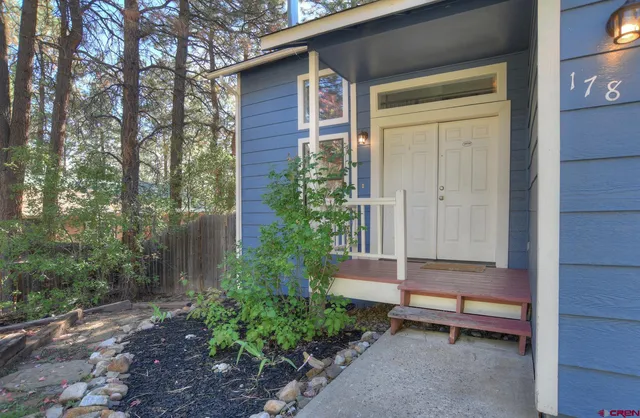 a backyard of a house with potted plants and large tree