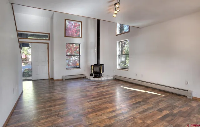 an empty room with wooden floor and windows