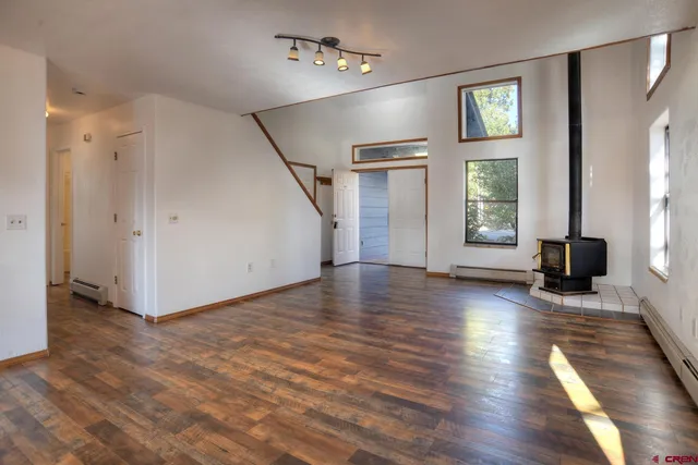 a view of an empty room with window and wooden floor