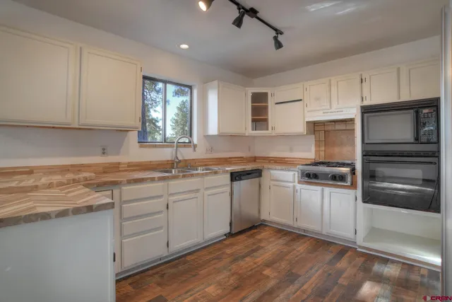a kitchen with granite countertop a sink stainless steel appliances and cabinets