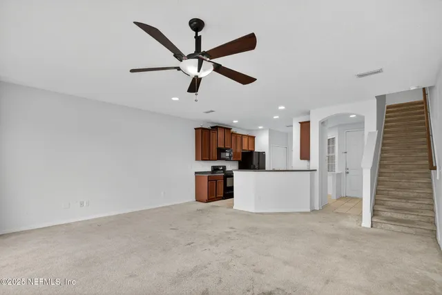 an empty room with ceiling fan and stainless steel appliances