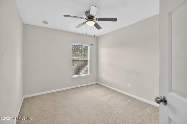 an empty room with a window and a ceiling fan