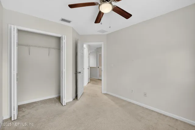 a view of an empty room and chandelier fan