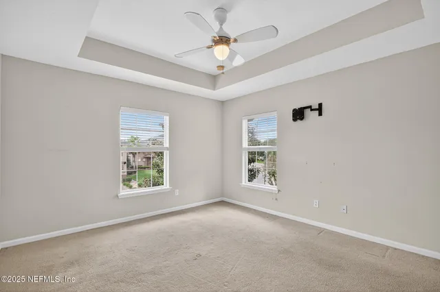 an empty room with windows and ceiling fan