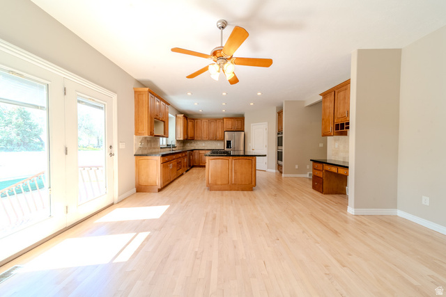 598 Hollow Creek Road Draper, UT 84020 - Photo 30 of 110 Expansive kitchen and living area featuring wood-finish flooring, a kitchen island with stone countertop, stainless steel appliances, and ample cabinetry