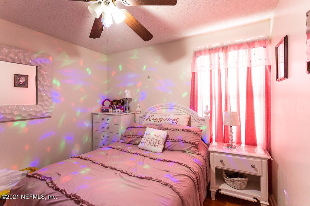 2450 Wattle Tree Road East Jacksonville, FL 32246 - Photo 8 of 24 a bedroom with a bed and a chandelier