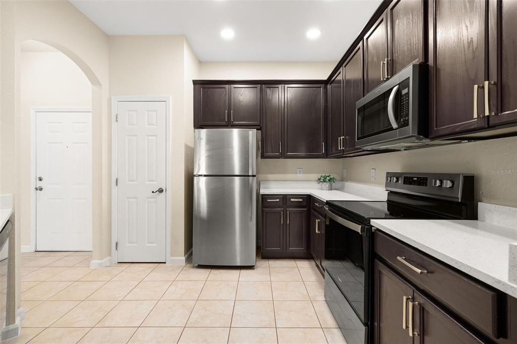 3001 Greystone Loop, Unit 106 Kissimmee, FL 34741 - Photo 5 of 27 a kitchen with stainless steel appliances granite countertop a refrigerator a stove a sink and a microwave