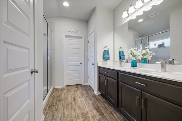 a spacious bathroom with a double vanity sink a mirror and shower