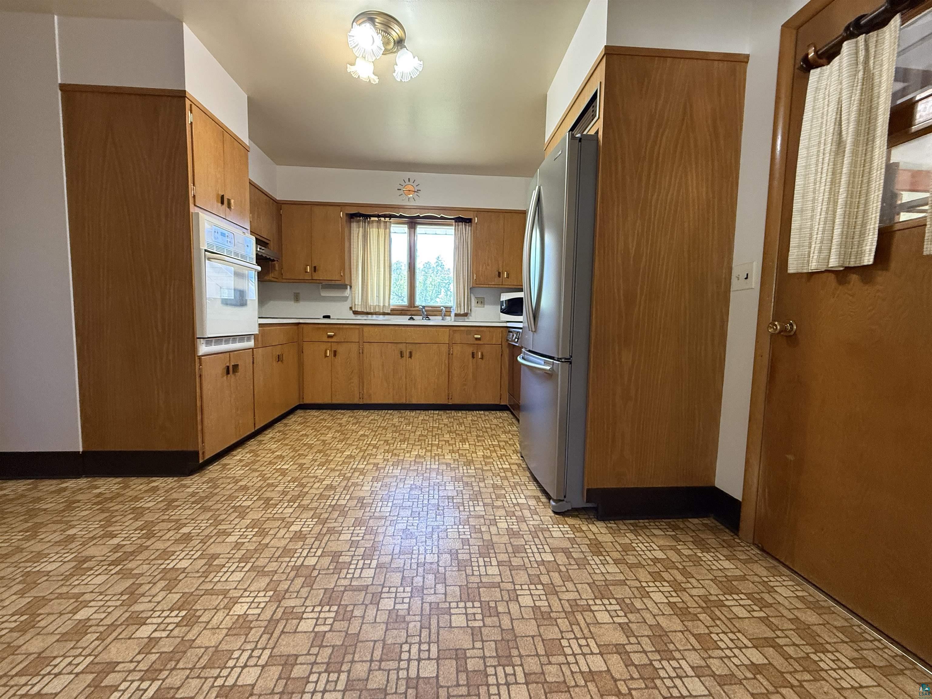 607 3rd Street Northeast Chisholm, MN 55719 - Photo 8 of 32 Spacious kitchen featuring extensive wood-finish cabinetry, a double wall oven, and patterned flooring