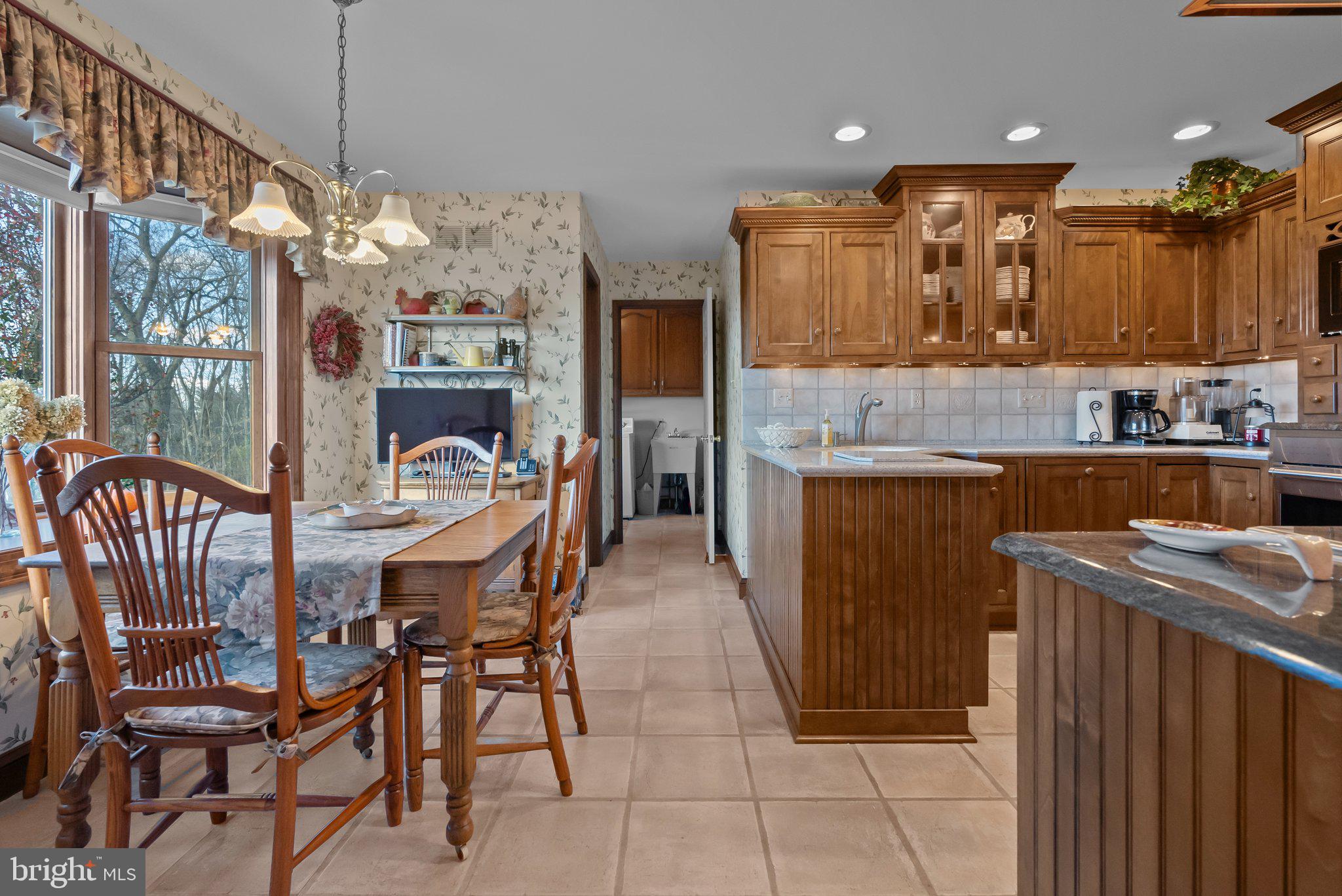 26 Hidden Turn Newtown, PA 18940 - Photo 9 of 40 a kitchen with stainless steel appliances kitchen island granite countertop a table chairs in it and wooden floors