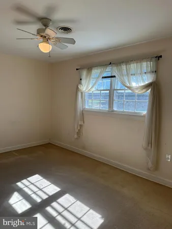 an empty room with a chandelier fan and windows