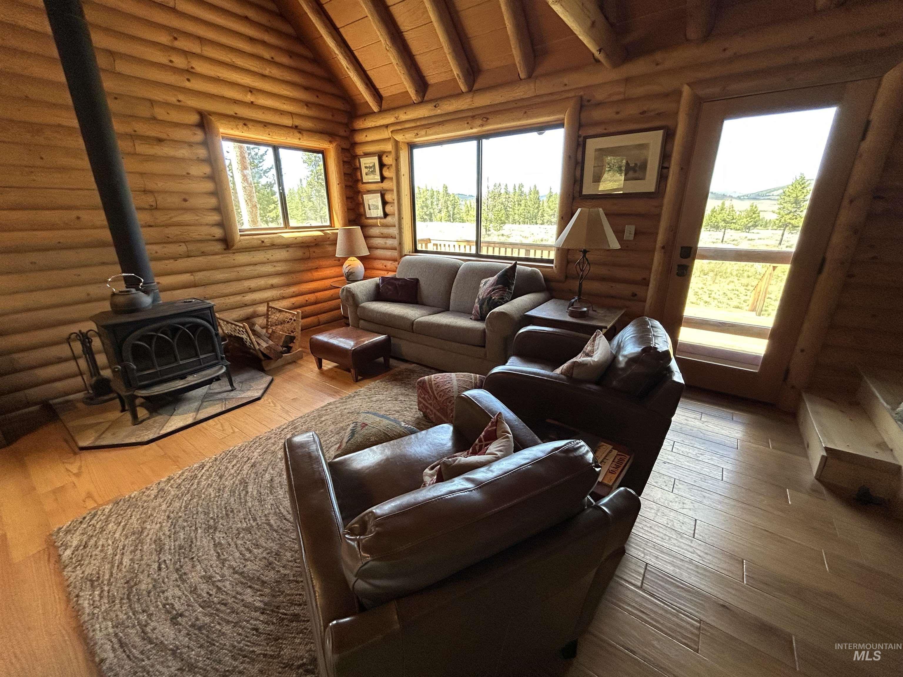 35 Sawtooth Way Stanley, ID 83278 - Photo 15 of 36 Living area featuring extensive log wall construction, wood-finish flooring, and a vaulted ceiling with exposed wood beams