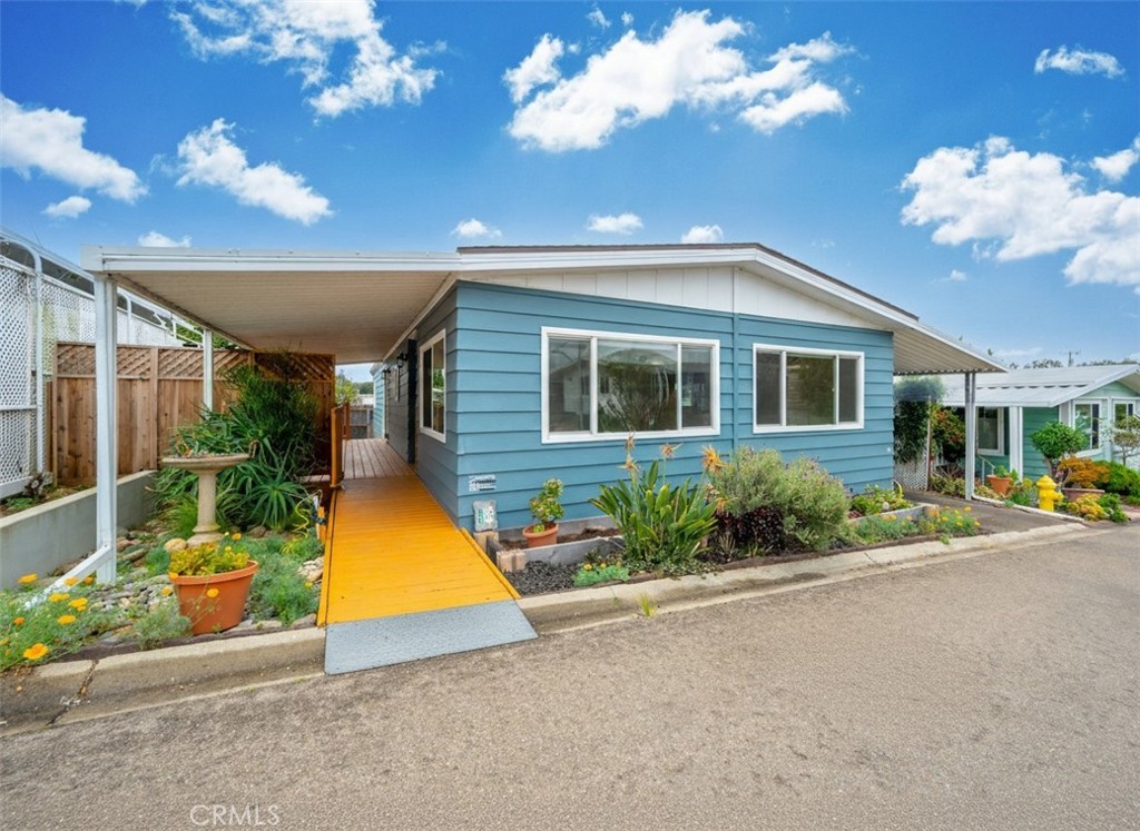 1675 Los Osos Valley Road, Unit 135 Los Osos, CA 93402 - Photo 1 of 38 Exterior – This home features freshly painted blue exterior siding with white trim, complemented by a covered carport and a welcoming entry deck. Entry is wheel chair accessible. No Stairs! The landscaped front area includes a variety of mature plants, adding color and curb appeal.