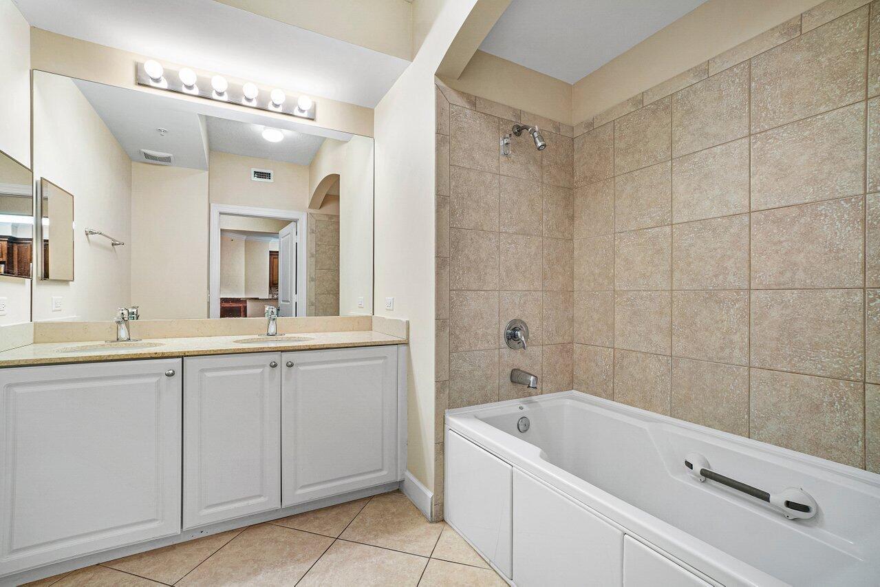 1690 Renaissance Commons Boulevard, Unit 1125 Boynton Beach, FL 33426 - Photo 17 of 37 a bathroom with a tub a double vanity sink and mirror